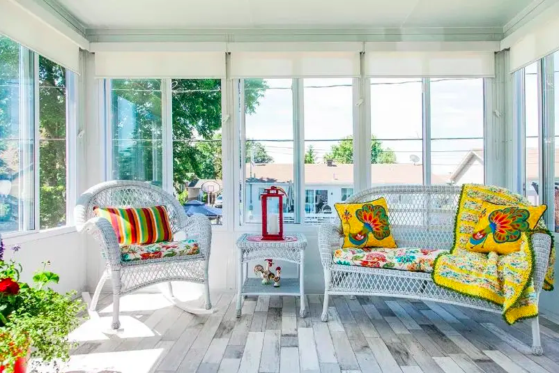 Solarium 3 saisons en verre avec de larges baies vitrées offrant une vue panoramique sur un jardin verdoyant.